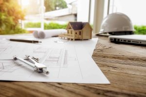Home construction plans with architectural drawings and house model on a desk