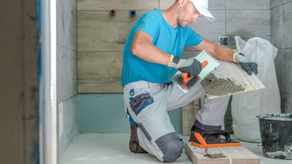 Builder applying tile adhesive while renovating a modern bathroom.